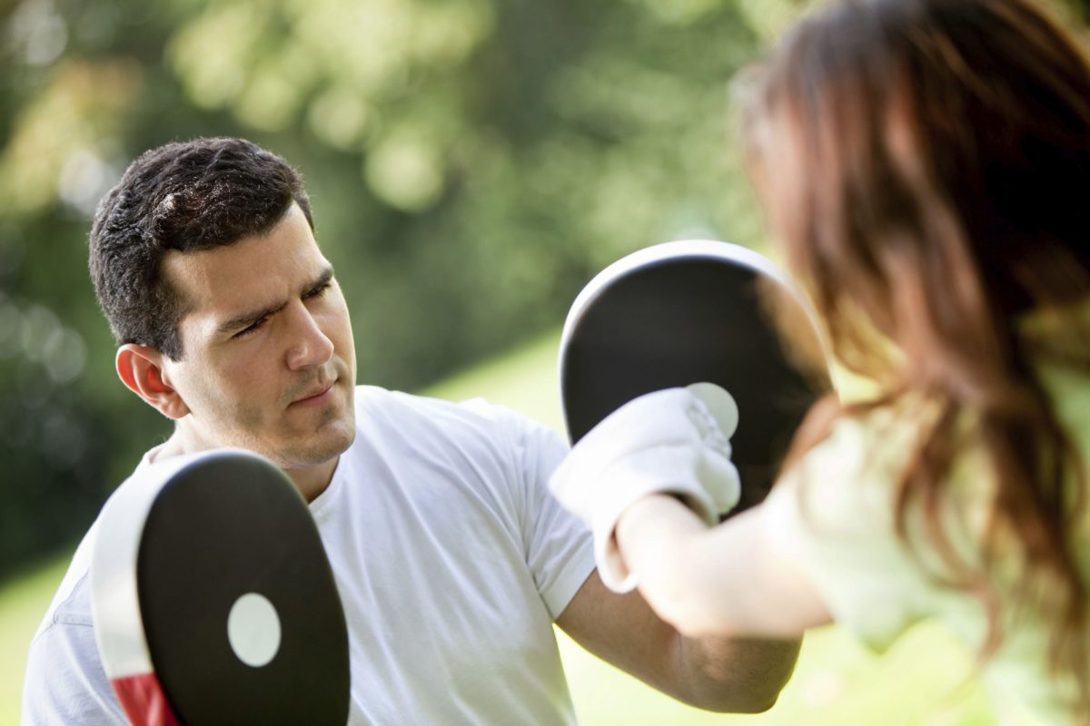 A coach focusing on teaching boxing to a long haired woman