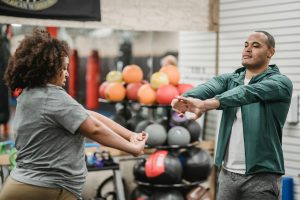 A personal trainer assisting his client in her warm up