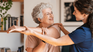 An old woman doing stretching with the help of a personal trainer