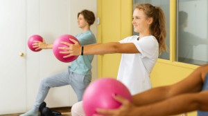 Teens doing squat exercise with exercise balls