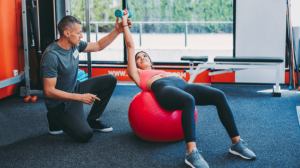 A personal trainer assisting a woman in her workout training