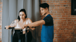 A personal trainer guiding his client in her workout
