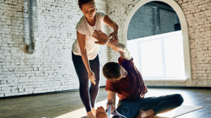 A personal trainer helping her male patient stretching