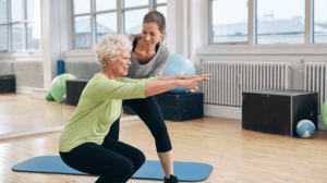 An old woman doing workout with her personal trainer assistance
