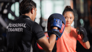 A personal trainer with boxing mitts spar with a lady