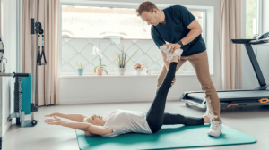 A personal trainer helping a client do stretching while lying down