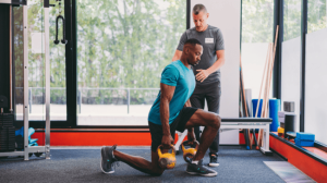 A man lifting kettlebells with his personal trainer guidance