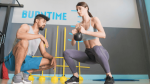A woman squatting while lifting a kettlebell
